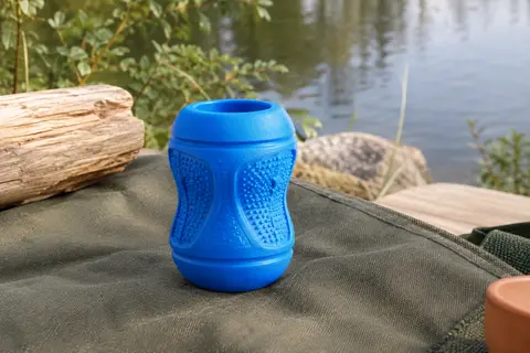Balle pour chien bleue en caoutchouc, à la forme de gobelet et à la surface texturée, près de l’eau.