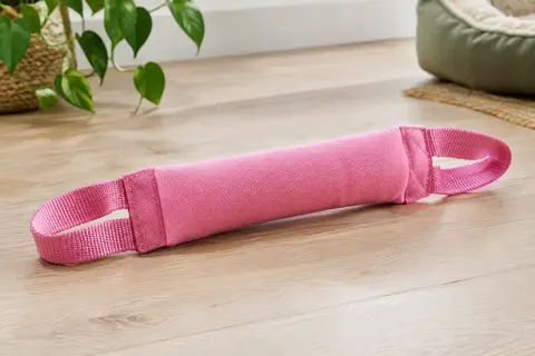 Boudin de traction rose en toile et nylon de 30 cm, avec deux anses intégrées, posé sur un sol clair.