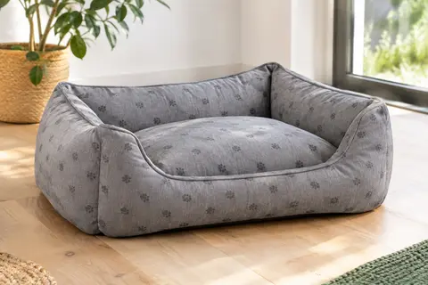 Panier pour chien gris à bords rehaussés et coussin imprimé, posé sur un sol clair.