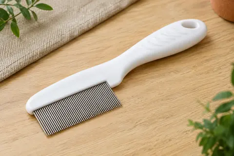 Peigne anti-puces blanc Redreo à dents métalliques rapprochées posé sur une table en bois clair